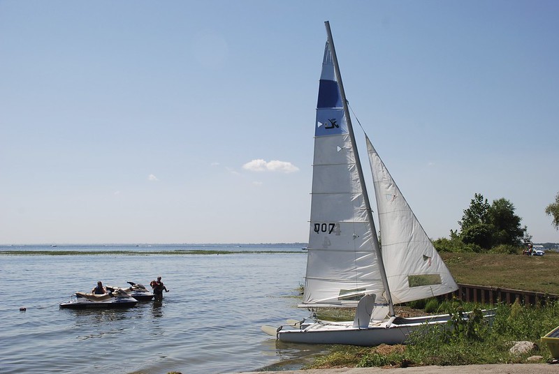 a sailboat docked on a beach with people swimming nearby